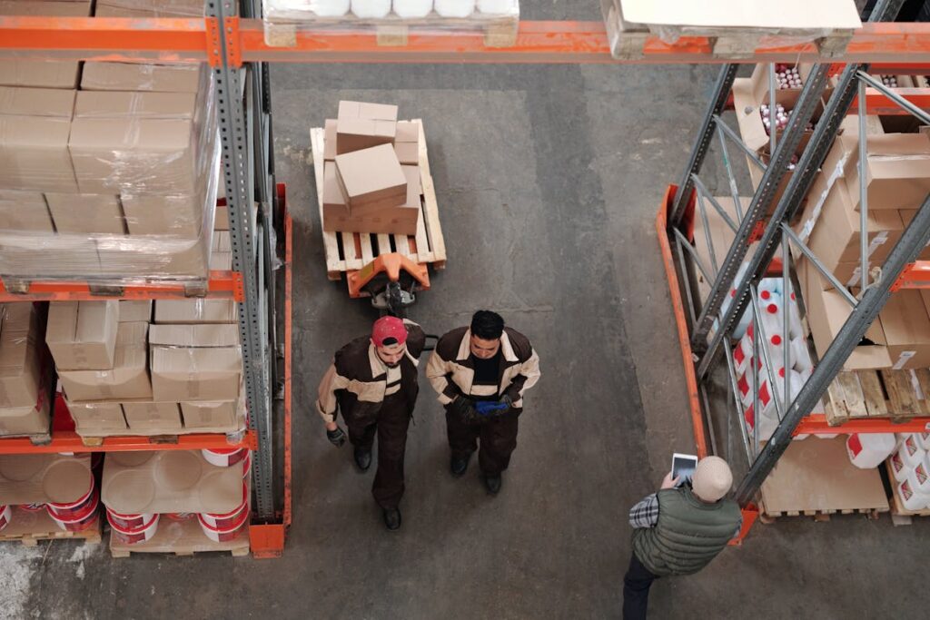 Workers hauling boxes on a pallet through a warehouse or fulfillment center