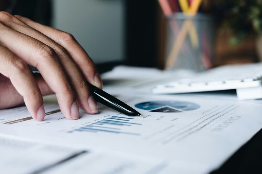 A hand pointing a pen at accounting charts.