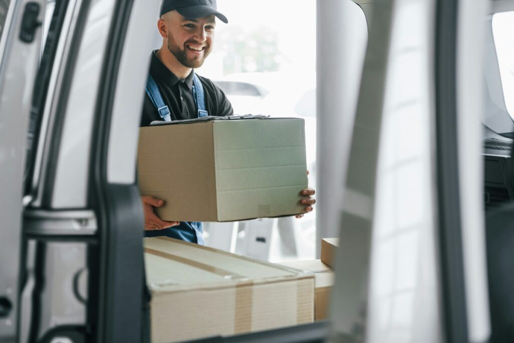 Smiling deliveryman taking a box from the back of a van