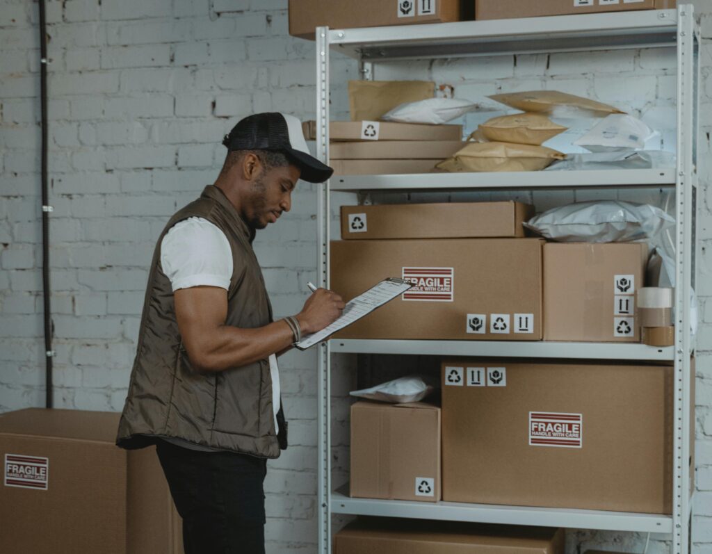 Man with clipboard checking labeled boxes before shipping